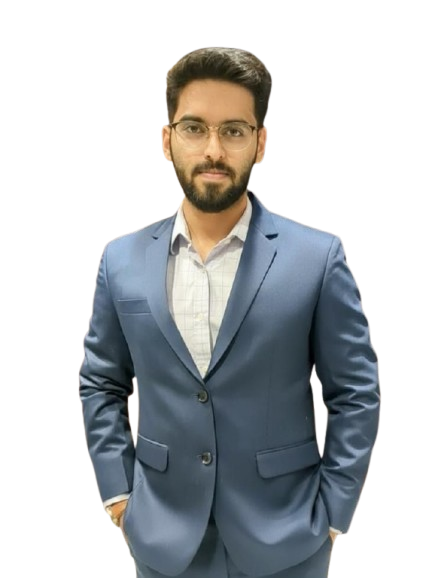 Professional headshot of young male team member in dark suit and glasses, neutral backdrop, confident folded-hands pose.